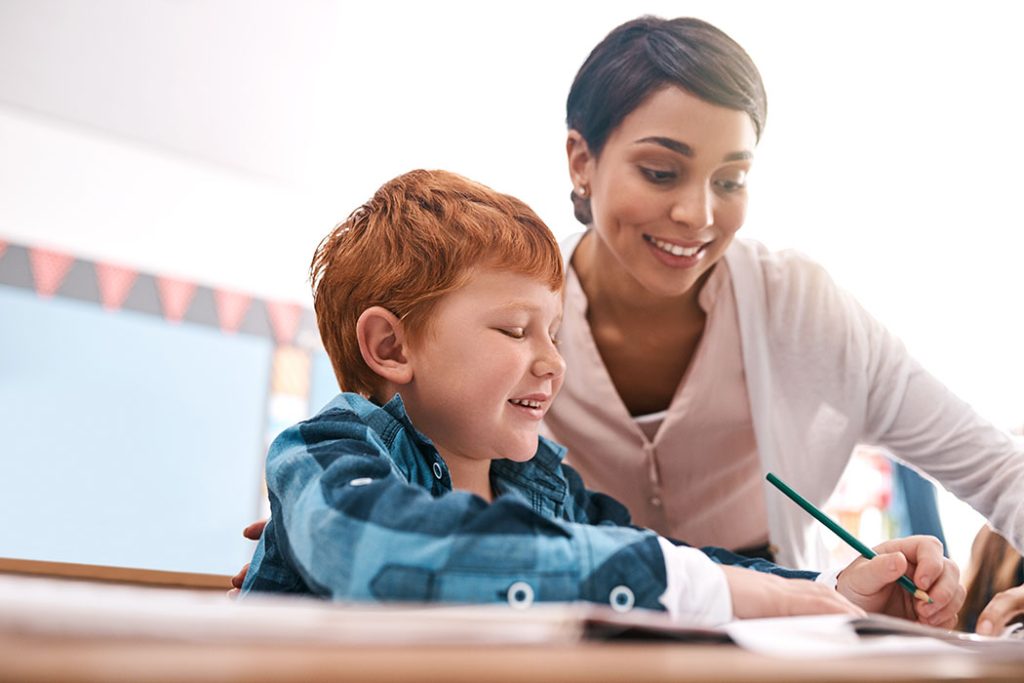 Shot of a cheerful young female teacher helping a student inside of the class at school